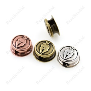 May include: Three metal beads with a warrior helmet design. The beads are in copper, brass, and silver tones.