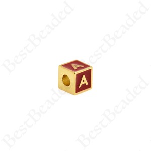 K&ouml;nnte beinhalten: Goldfarbener Buchstabenperle mit roter Emaille-Beschichtung. Der Buchstabe "A" ist in Gold auf die Perle gedruckt.
