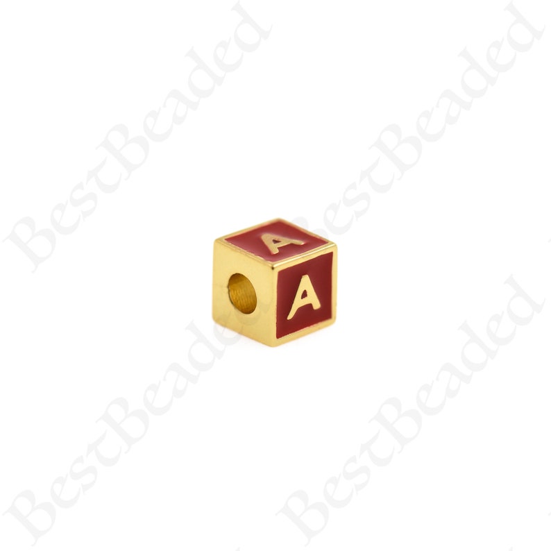 K&ouml;nnte beinhalten: Goldfarbener Buchstabenperle mit roter Emaille-Beschichtung. Der Buchstabe "A" ist in Gold auf die Perle gedruckt.