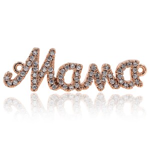 Puede incluir: Encanto de oro rosa con la palabra "Mama" escrita en cursiva y engastada con piedras de circonita c&uacute;bica transparentes.