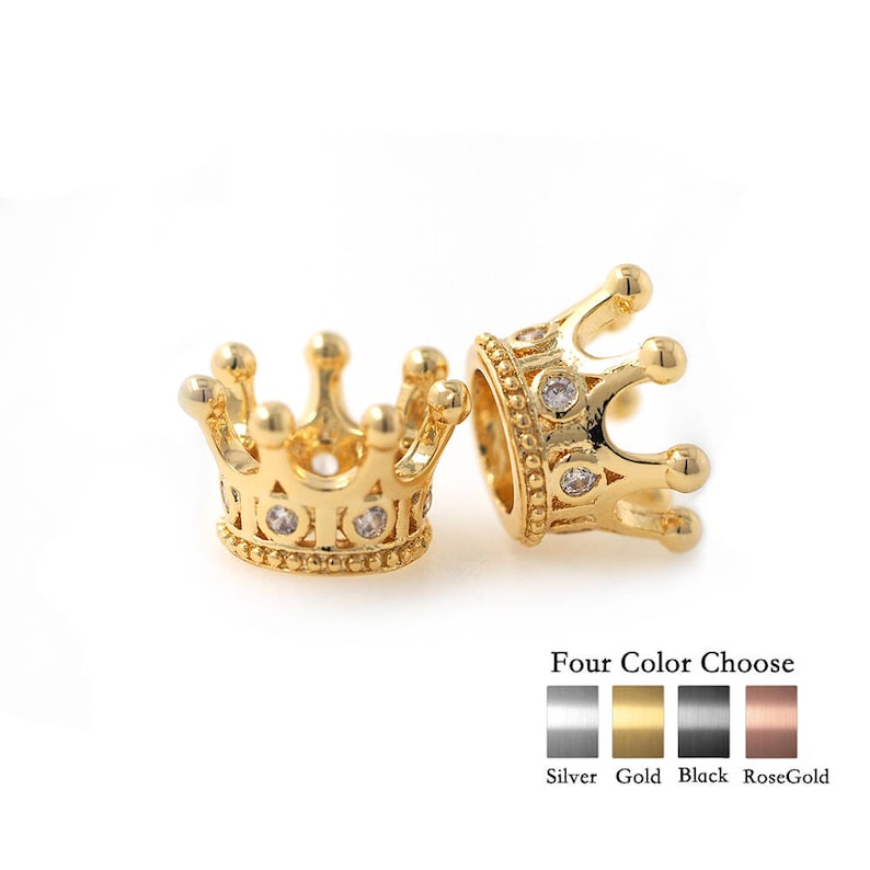 May include: Two gold-tone crown-shaped bead charms with clear cubic zirconia stones. The charms are available in four colors: silver, gold, black, and rose gold.