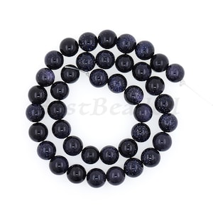 May include: A strand of dark blue round beads with a speckled, starry appearance. The beads are made of natural stone and are approximately 8mm in diameter.