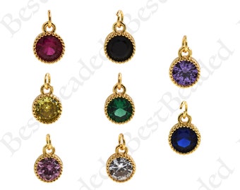May include: Assortment of eight gold-tone pendant charms with different colored crystal stones. The charms feature a round, bezel-set stone with a decorative border.