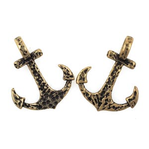 May include: Two gold-toned metal anchor charms with a textured surface.