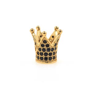 May include: A gold crown charm with black cubic zirconia stones. The crown is a popular charm for jewelry making and is a symbol of royalty.