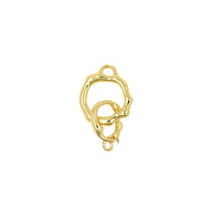 May include: A gold-colored jewelry clasp with an organic, flowing design. The clasp features two interlocking loops, one larger and irregularly shaped, and a smaller, more detailed loop. The piece has a polished finish and is set against a white background.