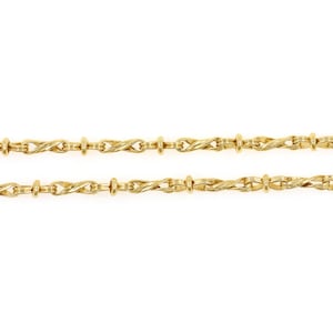 May include: A close-up of two gold-colored necklaces. The necklaces have a repeating pattern of twisted links and small cylindrical beads. The background is plain white.