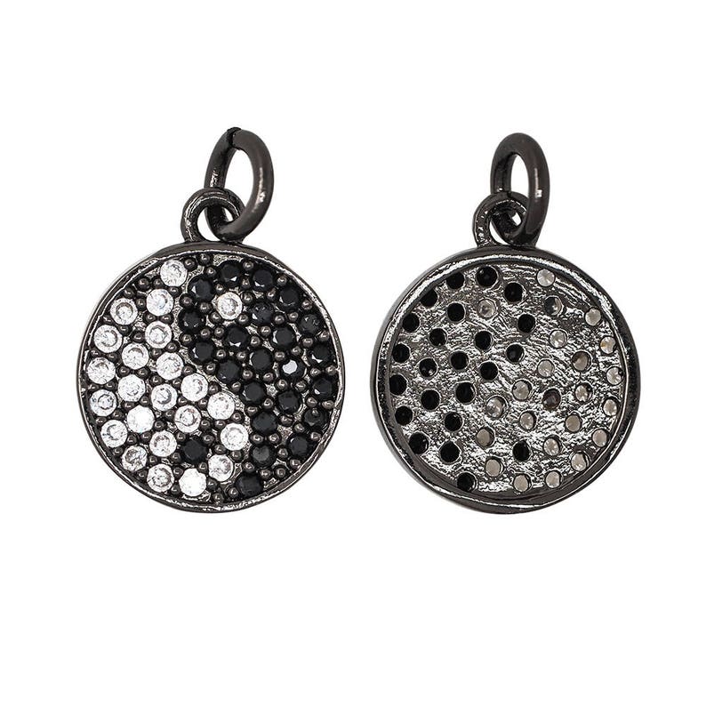 May include: Two black metal charms with a yin yang design. One charm has black and white stones, the other has a black and white dotted pattern.
