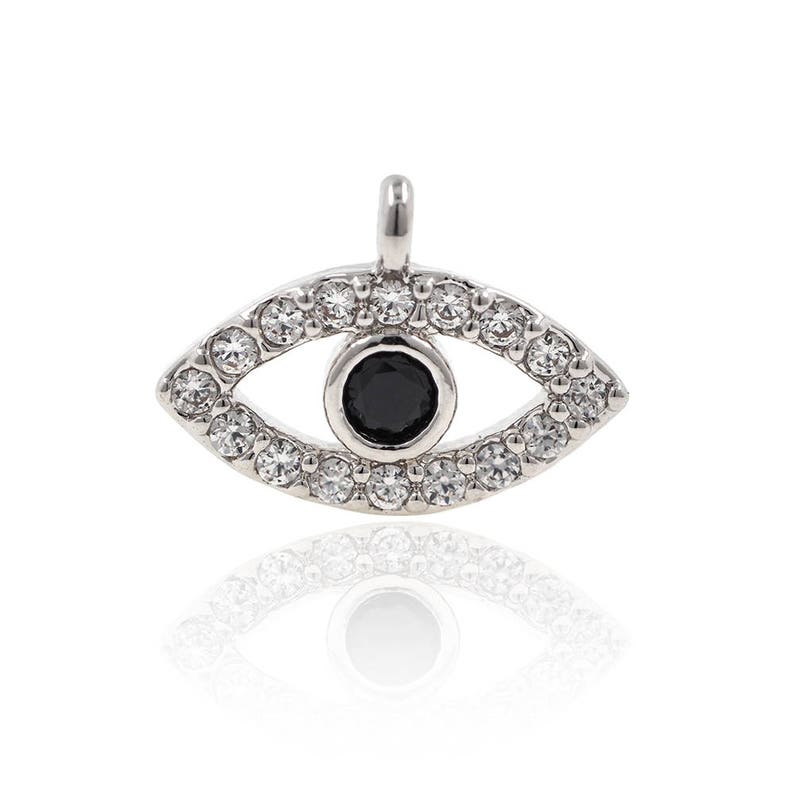 May include: Silver charm featuring a black evil eye design surrounded by clear cubic zirconia stones.