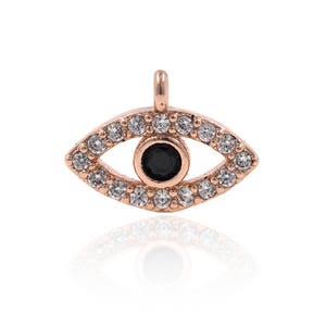 May include: A rose gold evil eye charm with a black centre and clear rhinestones around the edge.