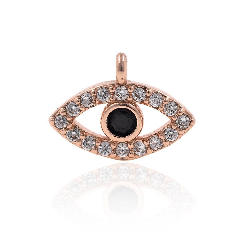 May include: A rose gold evil eye charm with a black centre and clear rhinestones around the edge.