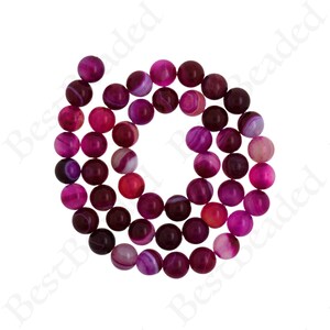 May include: A strand of pink and purple agate beads. The beads are round and have a smooth, polished finish. They are perfect for making jewelry or other crafts.