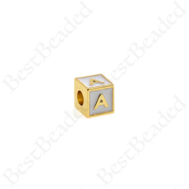 K&ouml;nnte beinhalten: Goldfarbener Alphabet-Perle mit einem wei&szlig;en Emaille-Buchstaben 'A' auf jeder Seite. Die Perle hat ein Loch zum Einf&auml;deln.