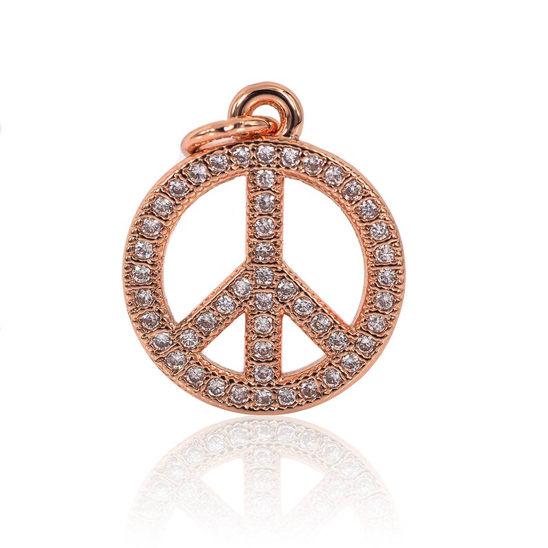May include: A rose gold peace sign pendant with clear cubic zirconia stones.