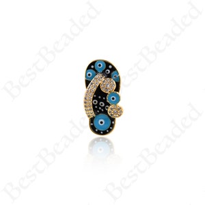 May include: Gold-tone charm featuring a black flip-flop with blue evil eye details and clear rhinestones.