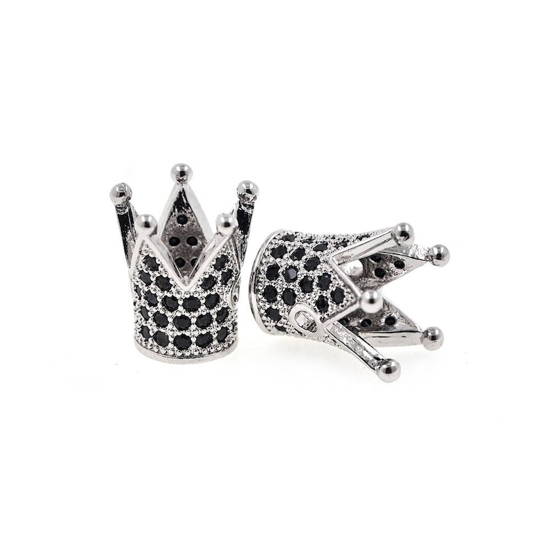 May include: Two silver crown-shaped bead caps with black cubic zirconia stones.