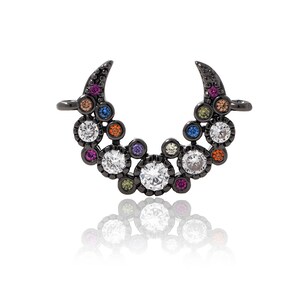 Puede incluir: Un dije de metal negro en forma de media luna con un grupo de piedras de cristal de colores y transparentes. El dije tiene un bucle a cada lado para sujetarlo a un collar o pulsera.