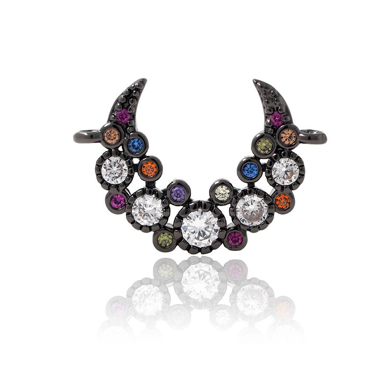 Puede incluir: Un dije de metal negro en forma de media luna con un grupo de piedras de cristal de colores y transparentes. El dije tiene un bucle a cada lado para sujetarlo a un collar o pulsera.