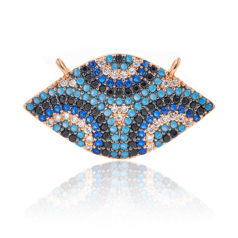 May include: A gold-toned pendant in the shape of an eye with blue, black, and white stones. The eye is a popular symbol of protection and good luck.