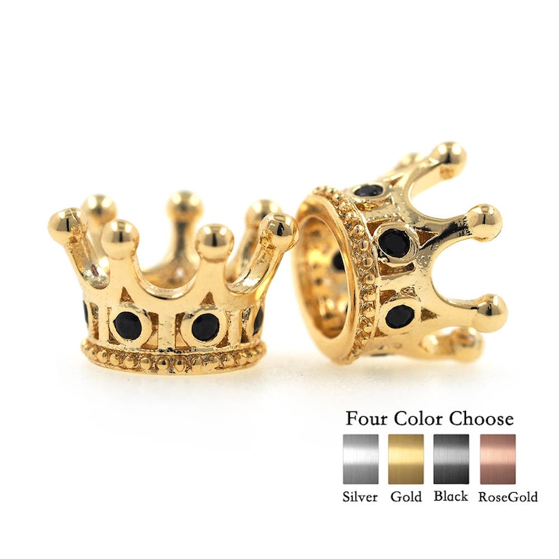 May include: Two gold-colored crown-shaped bead charms with black enamel accents. The charms are available in four colors: silver, gold, black, and rose gold.