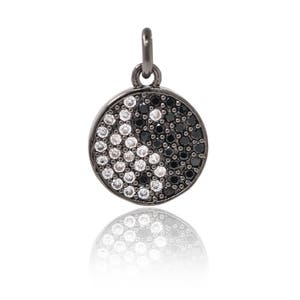 May include: A black pendant with a yin yang symbol design, featuring black and white cubic zirconia stones.