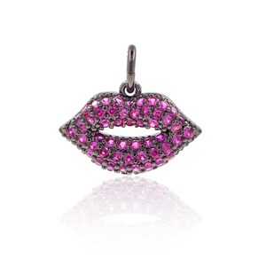 May include: A black metal charm in the shape of a pair of lips, encrusted with pink gemstones.