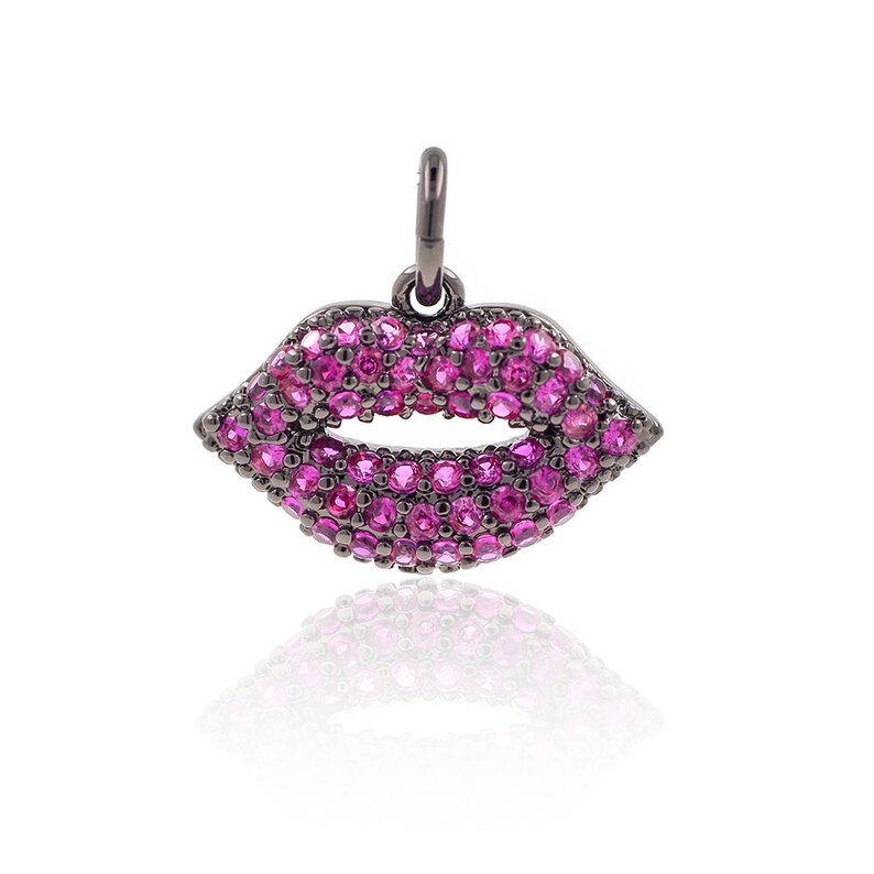 May include: A black metal charm in the shape of a pair of lips, encrusted with pink gemstones.