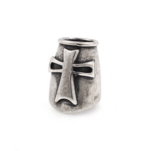 May include: A silver-toned bead with a cross design. The bead has a cylindrical shape with a textured surface and a prominent cross emblem on the front. The cross is slightly raised and has a detailed, aged appearance.
