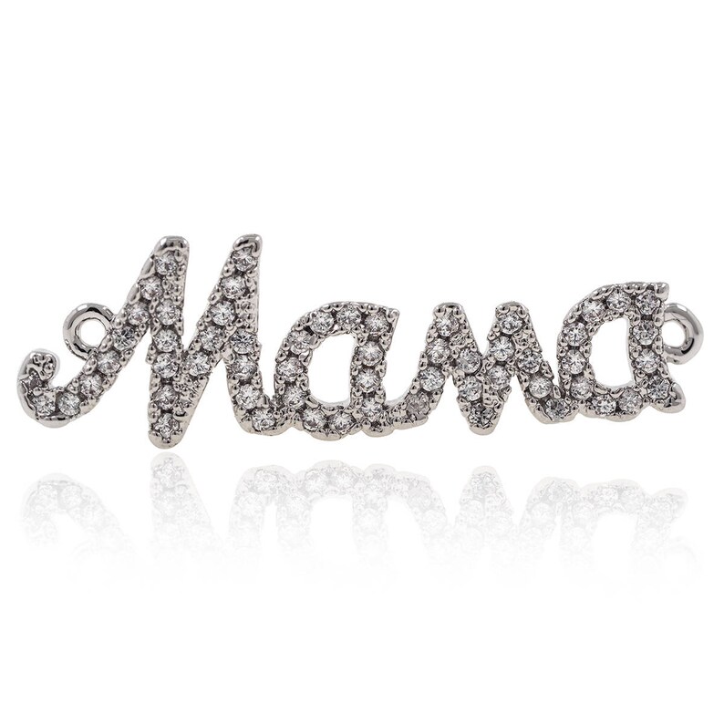 Puede incluir: Encanto de plata con la palabra "Mama" escrita en cursiva y decorada con peque&ntilde;os diamantes de imitaci&oacute;n transparentes.