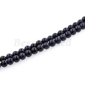May include: A strand of dark blue round beads with a speckled texture. The beads are strung on a clear thread.