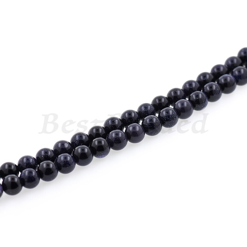 May include: A strand of dark blue round beads with a speckled texture. The beads are strung on a clear thread.