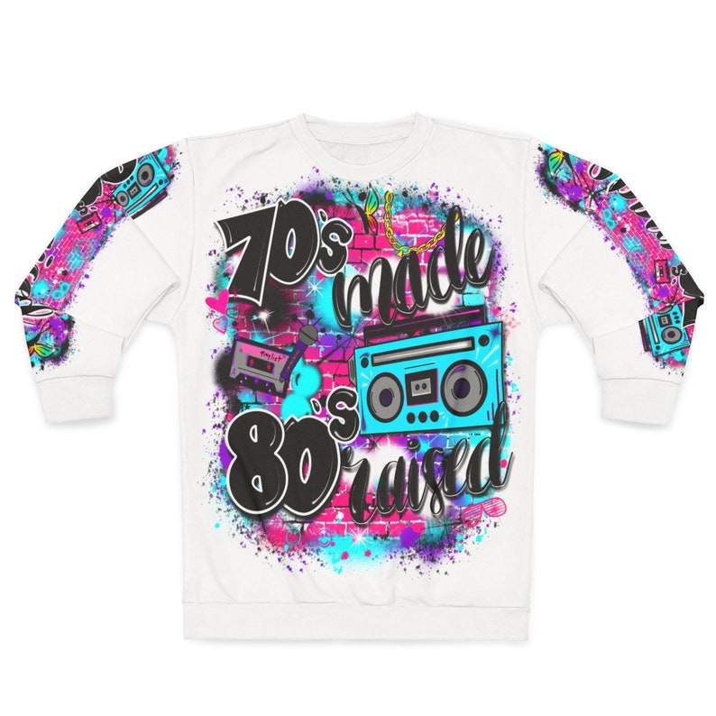 May include: White sweatshirt with a colorful graphic print featuring the text "70's made 80's raised" with a boombox and cassette tape.