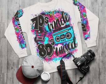 May include: White sweatshirt with a colorful graphic print featuring the text "70's made 80's raised" and a retro boombox and cassette tape.