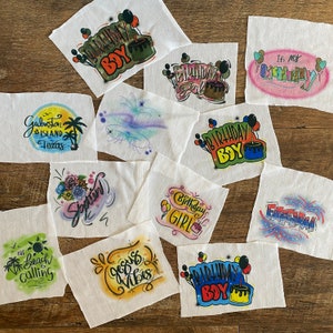 May include: Ten different iron-on transfers for t-shirts. The designs include birthday boy, birthday girl, fireworks, and a beach scene. The transfers are printed on white fabric.