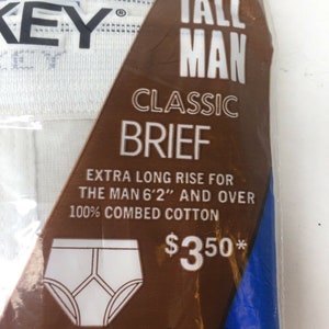 May include: A brown and blue package with white text that reads "Tall Man Classic Brief" and "Extra Long Rise for the Man 6'2" and Over 100% Combed Cotton &pound;350*"