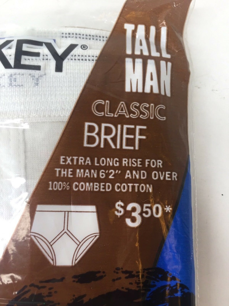 May include: A brown and blue package with white text that reads "Tall Man Classic Brief" and "Extra Long Rise for the Man 6'2" and Over 100% Combed Cotton &pound;350*"