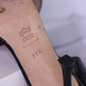 Puede incluir: Primer plano de la plantilla de un zapato de cuero negro. La plantilla es de color marr&oacute;n y tiene el texto "Vero Cuoio" y "Made in Italy" impreso en ella. La talla del zapato es 37 1/2.