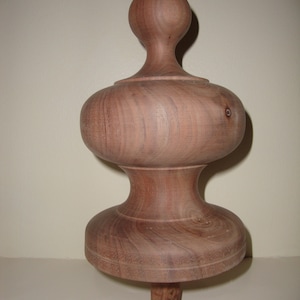 Op de afbeelding: Een houten bekroning met een afgeronde bovenkant en een bolvormige basis. De bekroning is gemaakt van lichtbruin hout met een gladde afwerking.