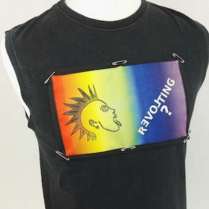 May include: Black sleeveless t-shirt with a rainbow graphic. The graphic features a sun-like figure with a mohawk and the word "REVOLTING?" in white. The graphic is attached with safety pins.