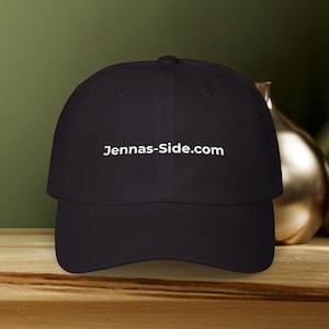 May include: Black baseball cap with the text "Jennas-Side.com" in white. The cap is made of a durable fabric and features a curved brim. The hat is a classic style, suitable for everyday wear.
