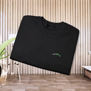 May include: Black t-shirt with a small green and yellow knife graphic.