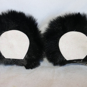 May include: Two black faux fur ear clips with white felt backing. The clips are attached to the back of the ear pieces.
