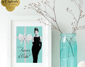 Op de afbeelding: Een witte rechthoekige fotolijst met een print op een turquoise achtergrond, een wit lint met strik en een zwart-witillustratie van een persoon in een zwarte jurk. De tekst Favors & Cake staat in zwarte sierletters aan de linkerzijde gedrukt.