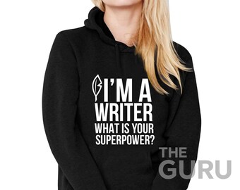 May include: Black hooded sweatshirt with the text "I'M A WRITER WHAT IS YOUR SUPERPOWER?" in white. A feather graphic is above the text. The word "THE GURU" is printed in white at the bottom right.