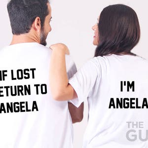 Könnte beinhalten: Zwei weiße T-Shirts mit schwarzem Text. Das erste Shirt sagt "Wenn verloren, zurück zu Angela". Das zweite Shirt sagt "Ich bin Angela".