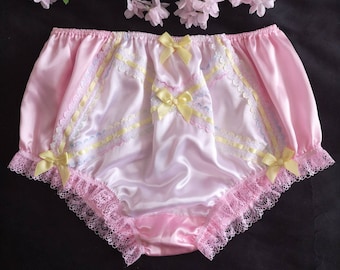 May include: Pink satin underwear with lace trim and yellow bows. The underwear features a ruffled lace edge and decorative lace panels with pastel ribbon accents. The design includes multiple yellow bows.