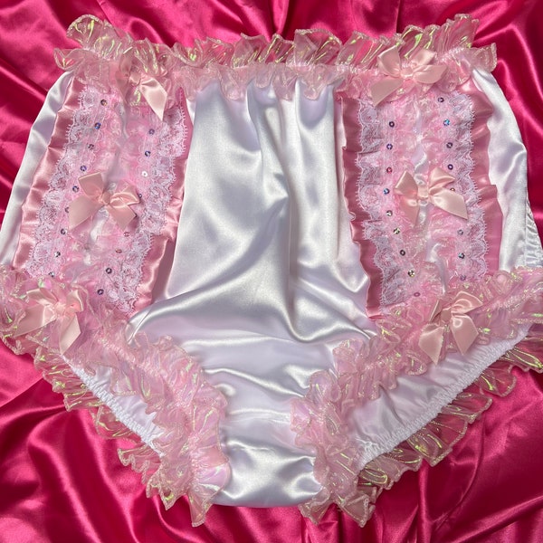 May include: White satin bloomers with pink lace and ruffle trim. The bloomers have a pink bow on each side and are decorated with sequins.