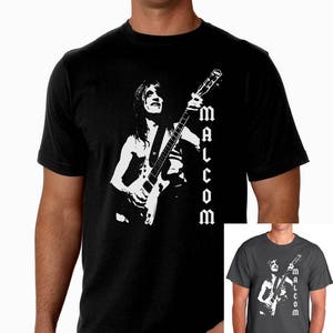 May include: Black t-shirt with a white silhouette of a person playing a guitar. The text "MALCOLM" is printed vertically on the right side of the shirt.