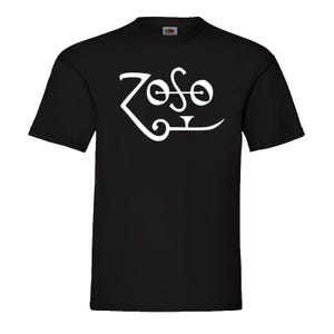 Può includere: T-shirt nera con grafica bianca "Zoso". Il design è un wordmark stilizzato con forme di lettere uniche. La maglietta è a girocollo.