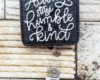 May include: Black and white glitter badge holder with a white embroidered quote that reads "Always stay humble & kind".